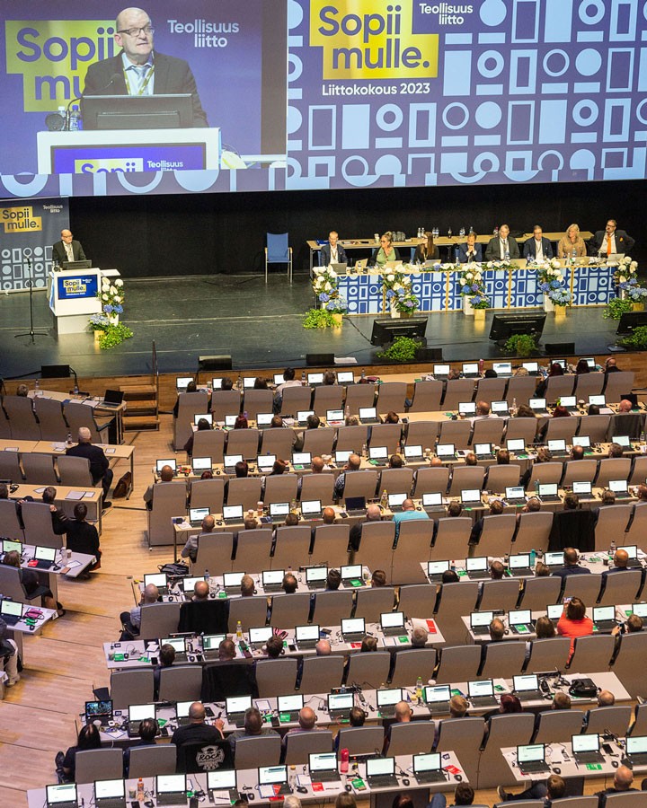 Auditorio, jonka penkeissä istuu Teollisuusliiton liittokokoukseen osallistujia tietokoneet edessään.